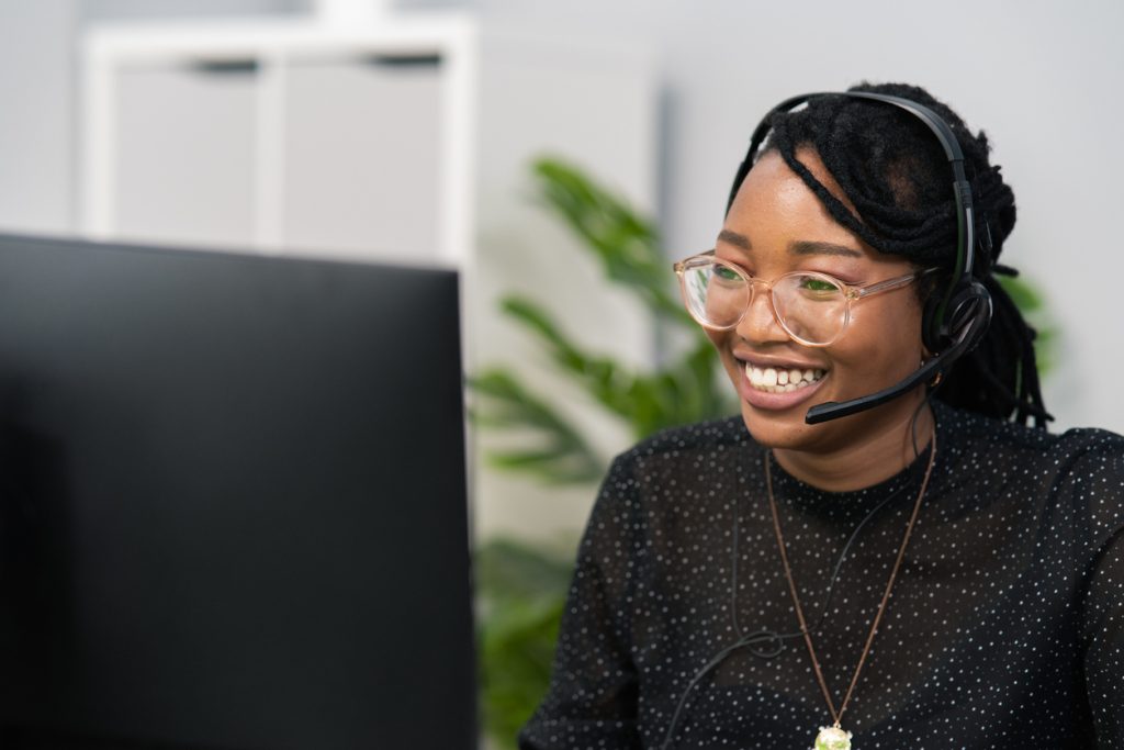 Woman wearing headset and smiling at computer screen