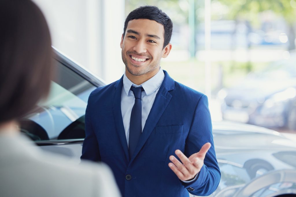 Car salesperson talking to customer in showroom