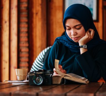 Woman wearing hijab reading book in cafe