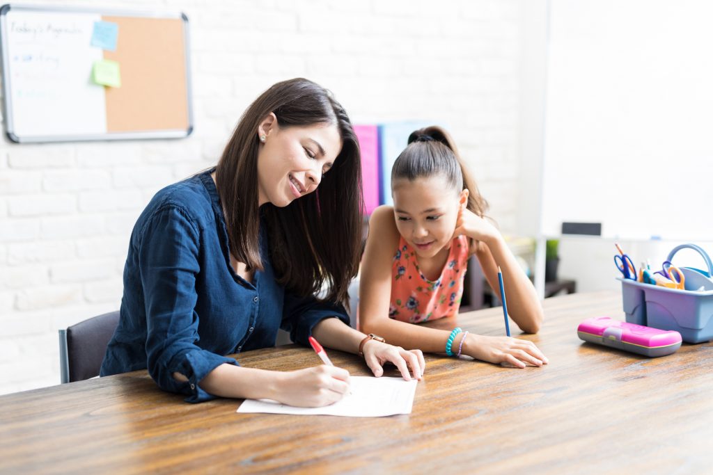 mother working on paper with daughter at table