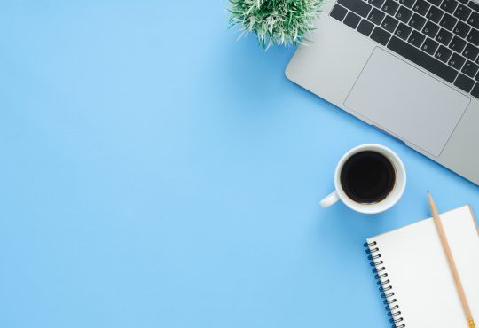 laptop and coffee mug from above on blue background