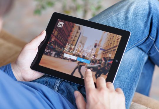 Man holding iPad with App LinkedIn on the screen