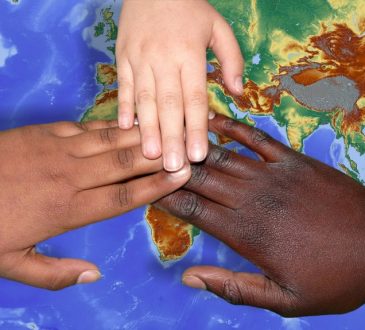 hands of different skin colours over a map