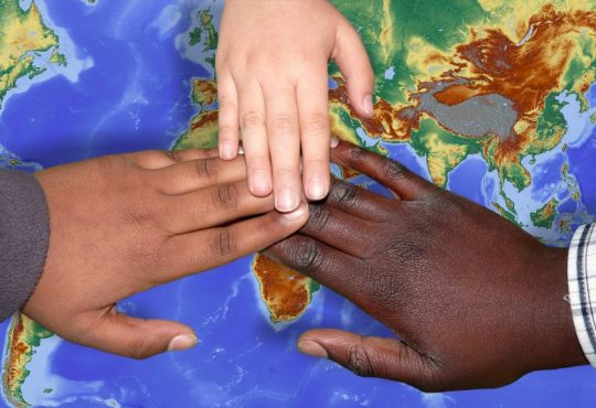 hands of different skin colours over a map