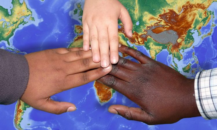 hands of different skin colours over a map