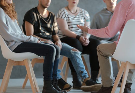 people sitting in chairs for group counselling session