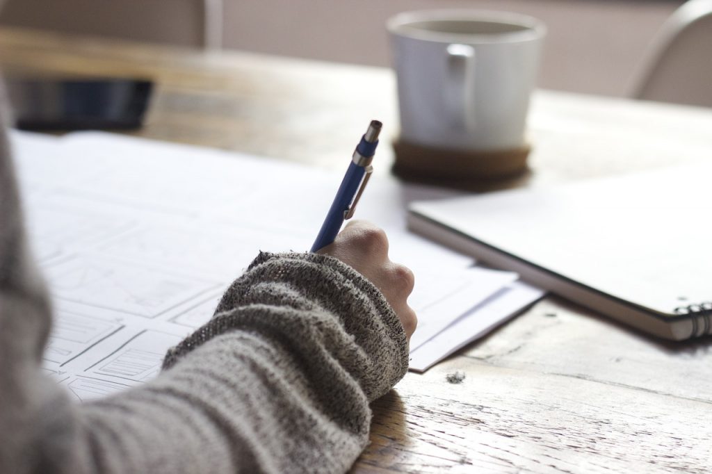 Closeup of person's hand writing in notebook