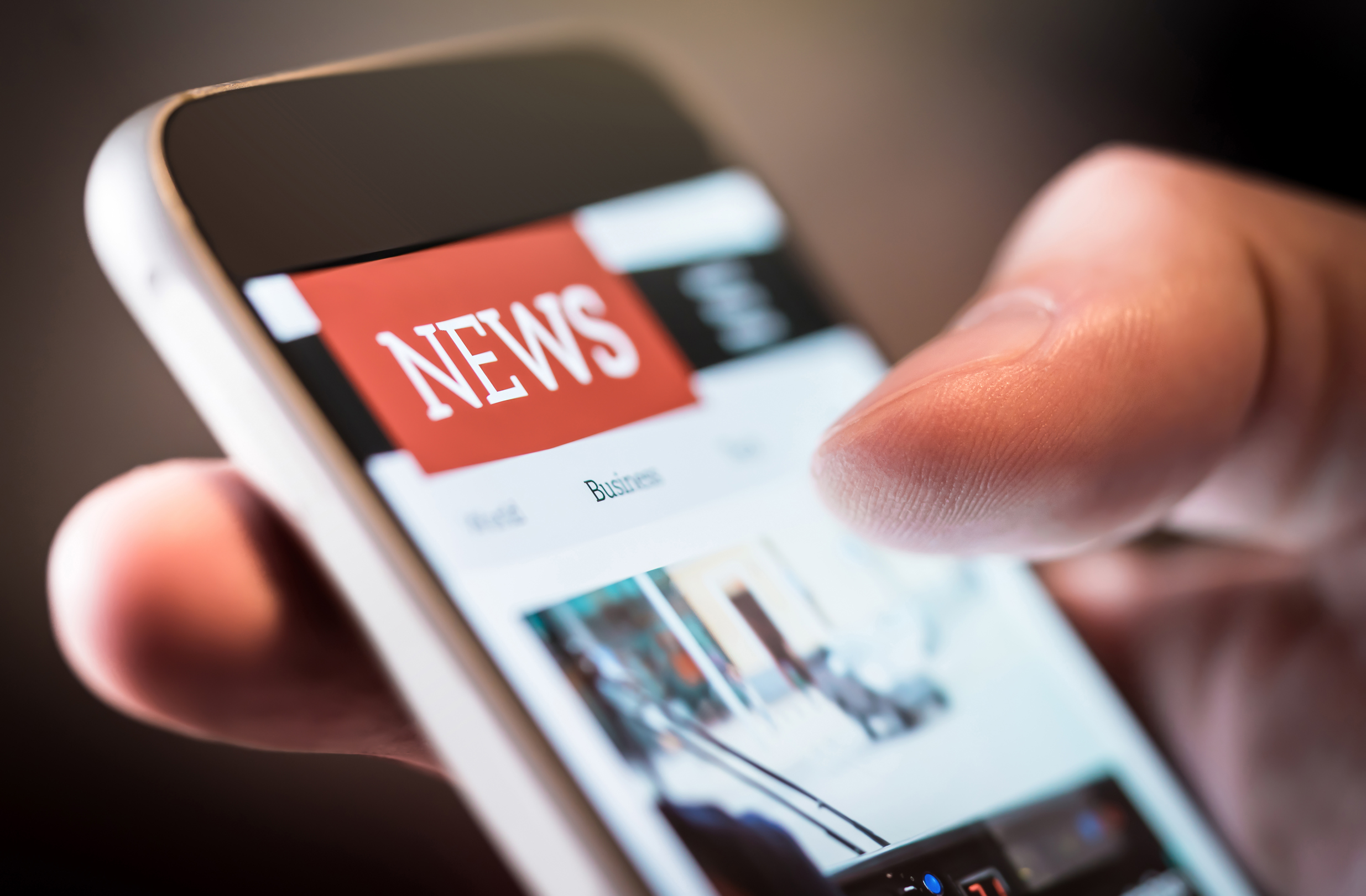 closeup of hand holding phone displaying news