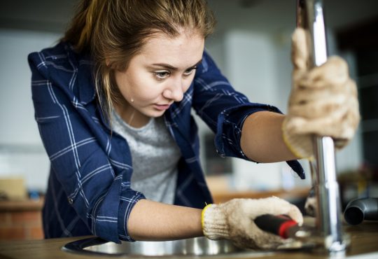 Woman fixing kitchen sink