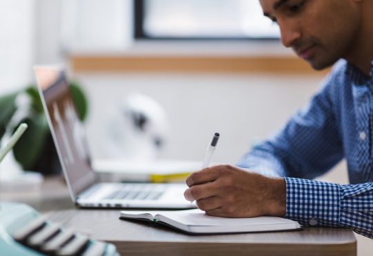 man writing in notebook