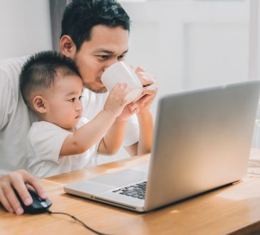 man with baby in lap working on computer
