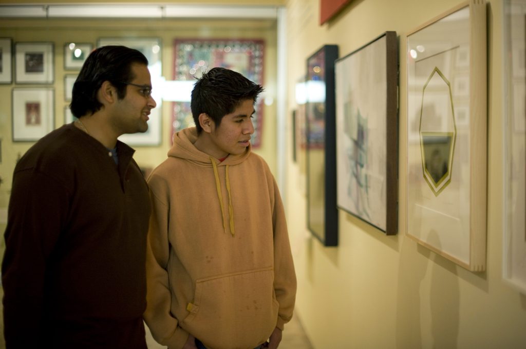 Male mentor and mentee looking at art in museum