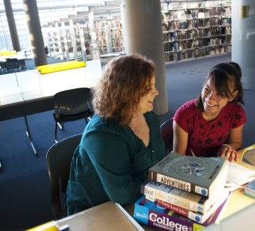 female mentor and mentee sitting together in library