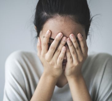 Young girl covering her face with her hands