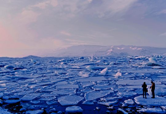 man and woman standing on broken ice in arctic