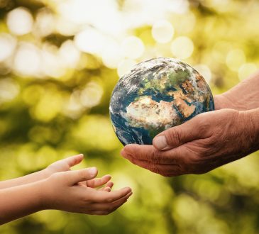 Close up of senior hands giving small planet earth to a child