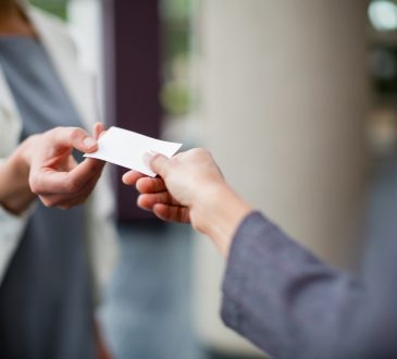 Close-up of business executives exchanging business card at conference centre