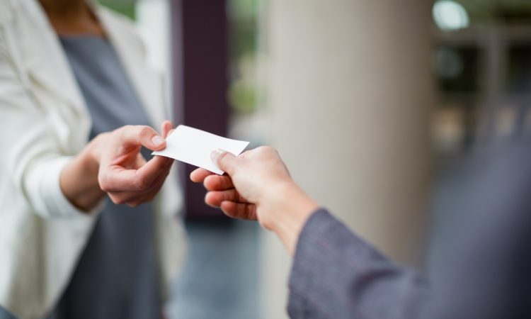 Close-up of business executives exchanging business card at conference centre