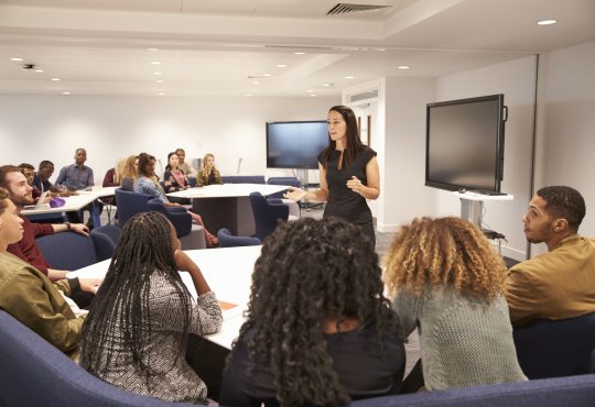 Female teacher addressing university students in a classroom