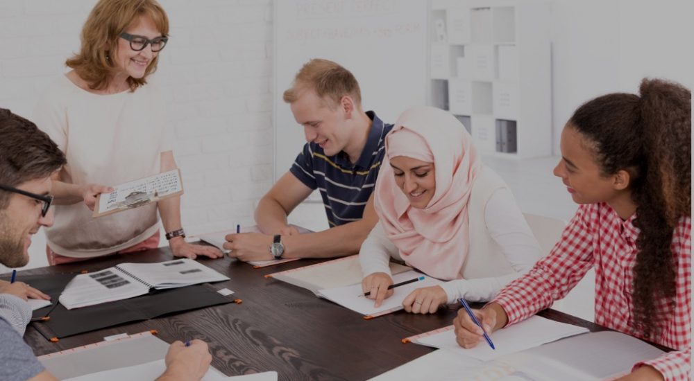 diverse group of people sitting around table listening to instructor