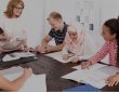diverse group of people sitting around table listening to instructor
