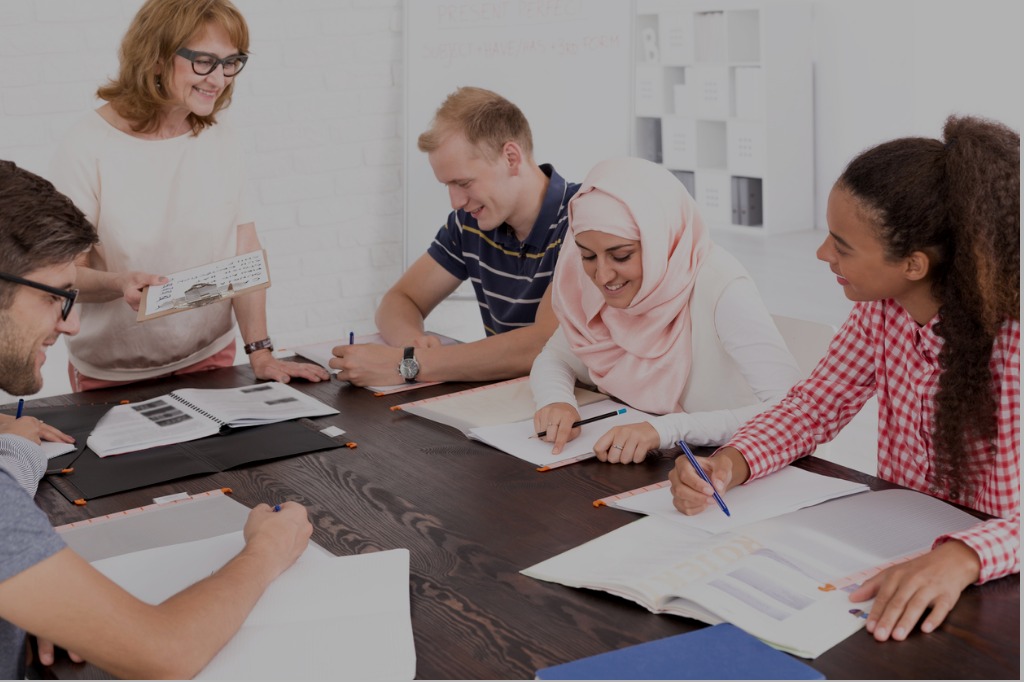 diverse group of people sitting around table listening to instructor