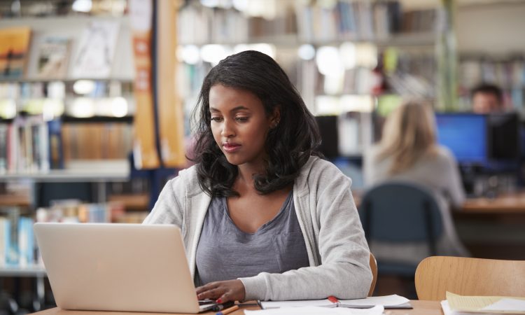 Female Student Working On Laptop In College Library
