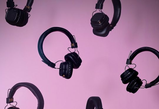 multiple pairs of over ear headphones floating on purple background