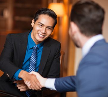 Closeup of two smiling business men shaking hands in cafe