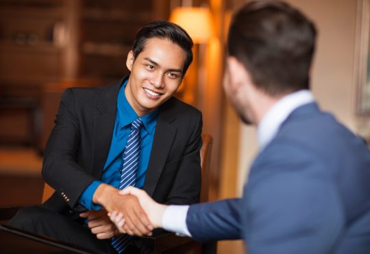 Closeup of two smiling business men shaking hands in cafe