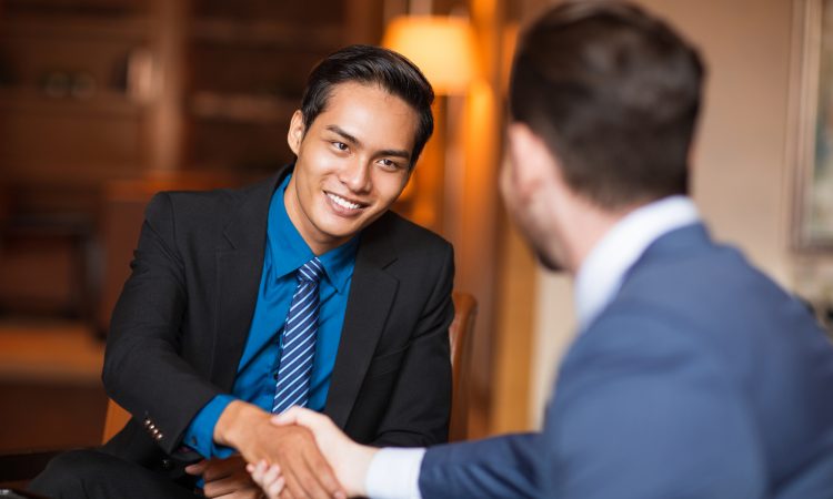 Closeup of two smiling business men shaking hands in cafe
