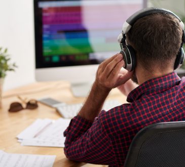 man sitting at desk wearing over-ear headphones