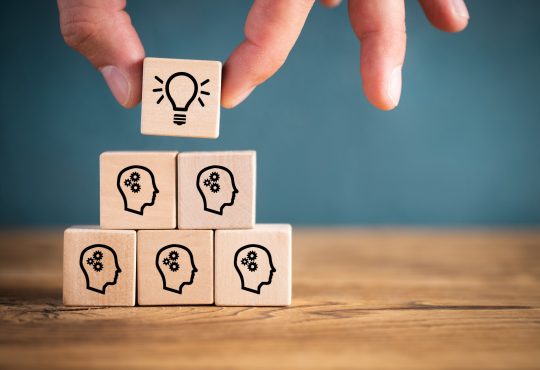 many people together having an idea symbolized by icons on cubes on wooden background