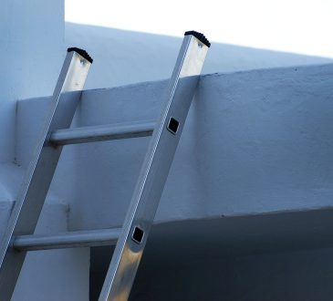 ladder propped up against white building