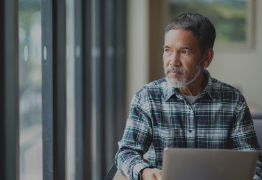 man sitting out computer looking out window