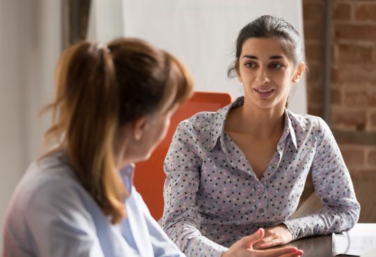 two women speaking in office