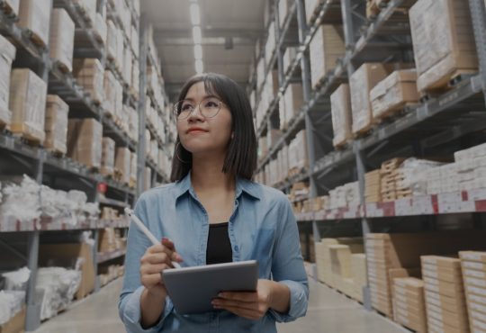 women in warehouse holding clipboard