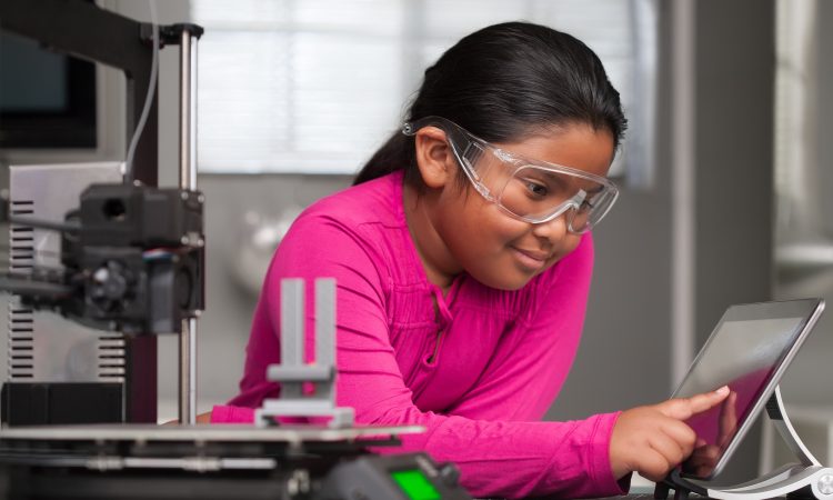 A young student wearing pink is working on a touchscreen making changes to a 3d printed toy in a summer school tech class.