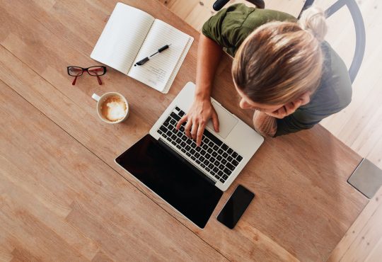 Top view of woman using laptop sitting at table