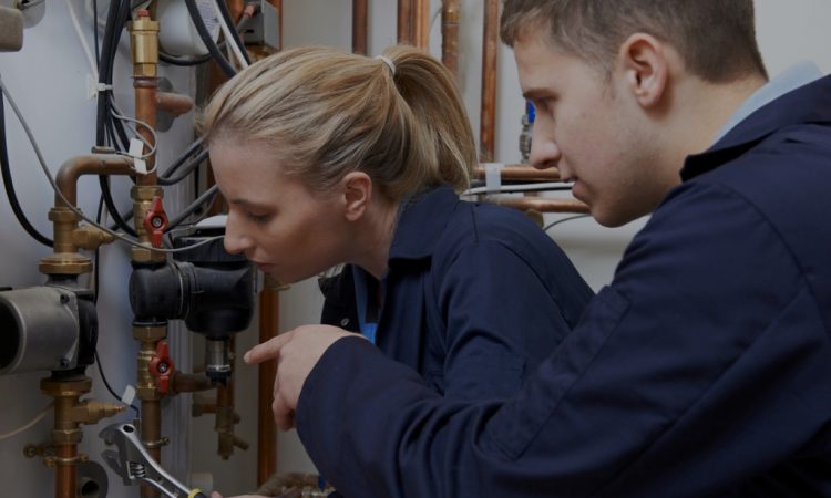 Two plumbing students looking at pipes