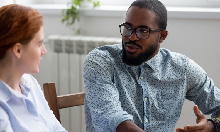man and woman sitting and talking in office