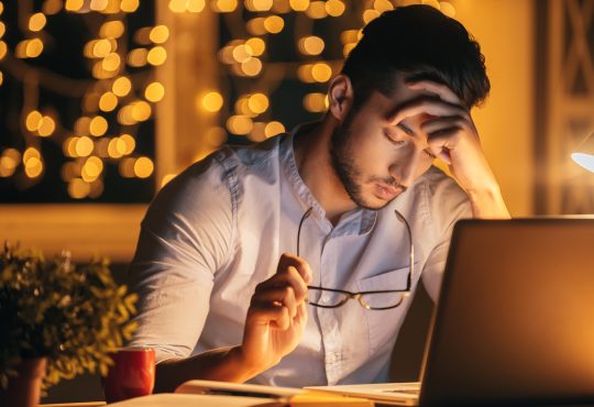 frustrated man with eyes closed in front of computer