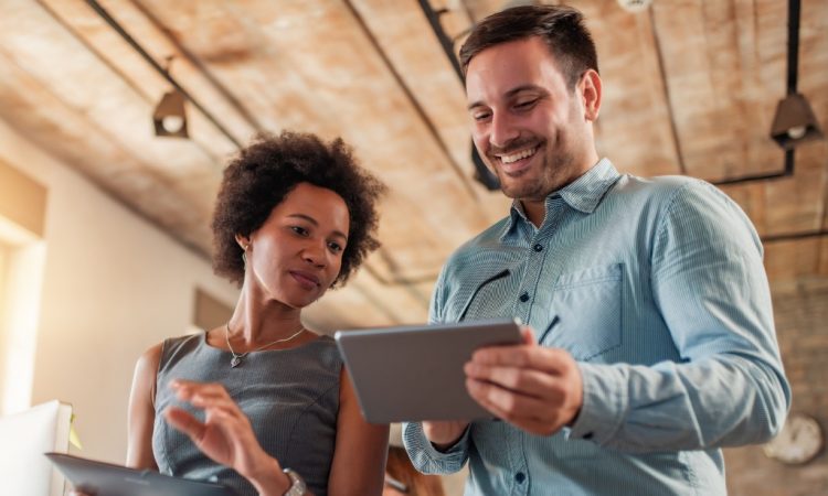 man and woman talking together in office looking at ipads