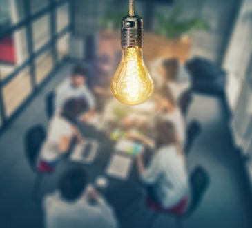 Light bulb hanging over people meeting at table