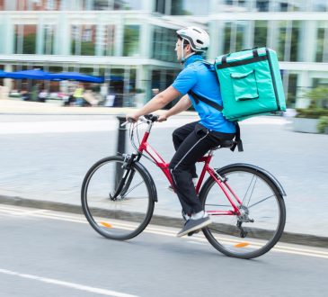 Courier On Bicycle Delivering Food In City
