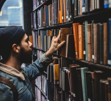 man looking at book in library