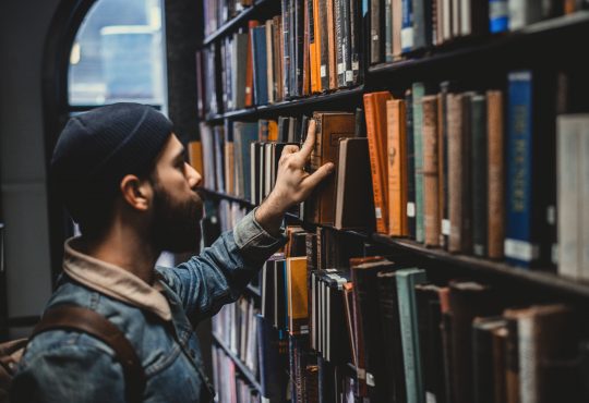 man looking at book in library