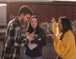 three young people talking by chain link fence