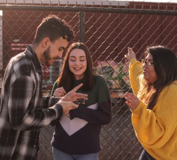 three young people talking by chain link fence