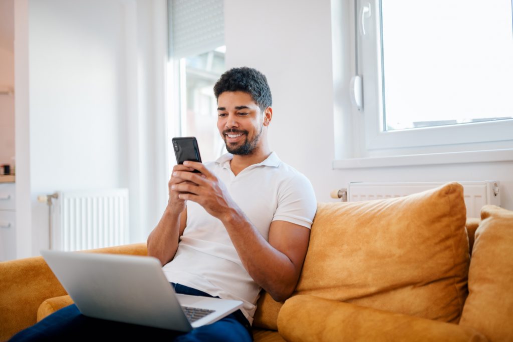 man sitting on couch smiling at phone